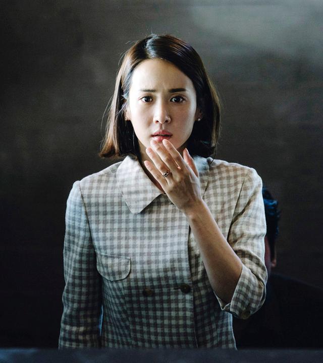 Eine Frau, die in einem modernen Haus auf einer Treppe aufwärts steht, die Hand vor den Mund geschlagen