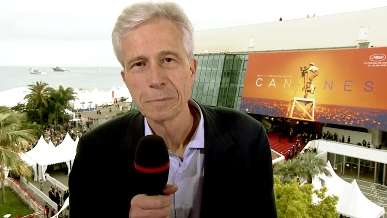 Mann mit weißen Haaren und Mikrofon vor dem roten Teppich der Filmfestspiele von Cannes