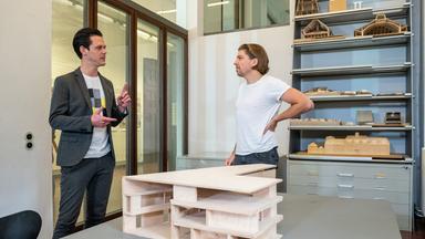 "zdf@bauhaus": Singer-Songwriter Philipp Poisel (rechts) im Interview mit Moderator Jo Schück (links). Im Hintergrund stehen Holz-Modelle im Regal. Vorne links ist ein Bildschirm, auf dem Philipp Poisel zu sehen ist.