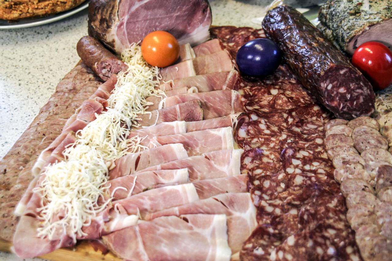 Holzbrett mit angerichtetem Schinken, Hartwurst und Kren.