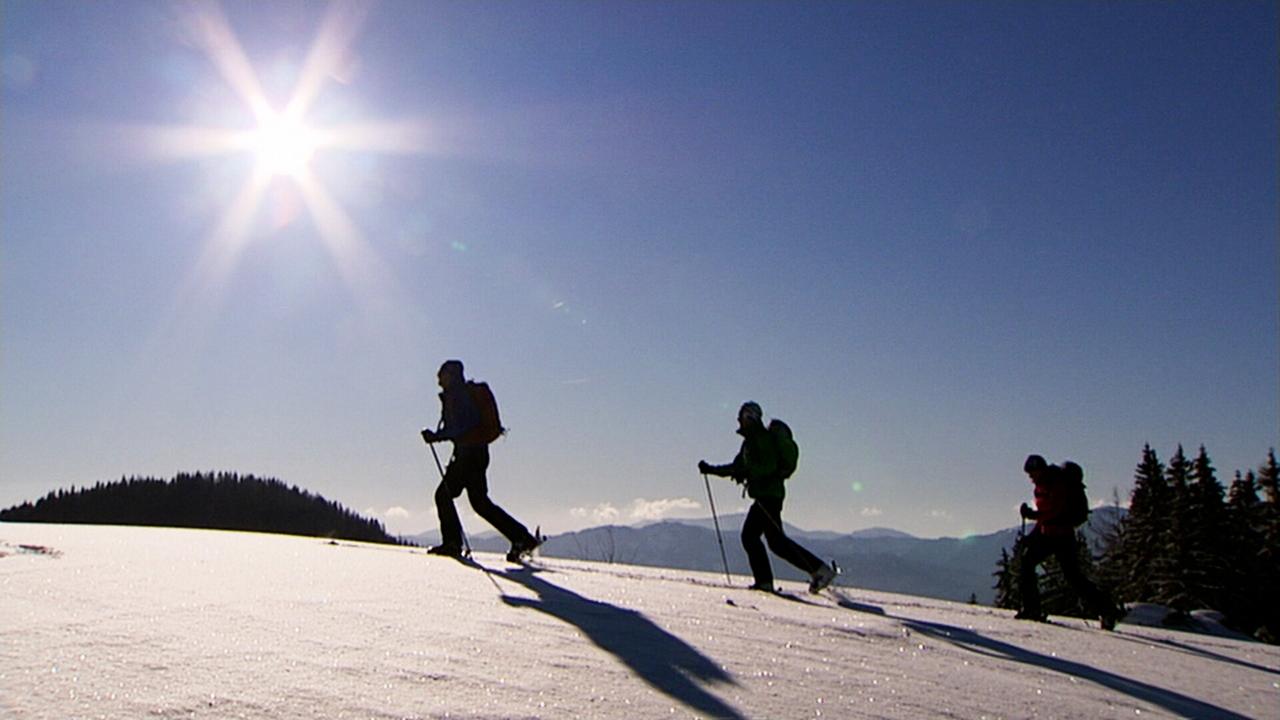 Ski-Bergwanderer auf verschneiten Bergen in gleißendem Sonnenlicht