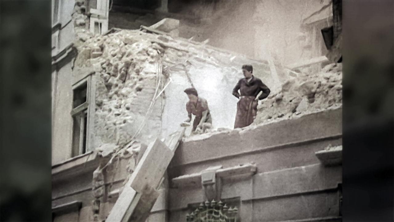 Frauen stehen auf den Mauern eines im 2. Weltkrieg zerstörten Hauses in Wien und lassen Steine über eine improvisierte Rutsche hinunter - 