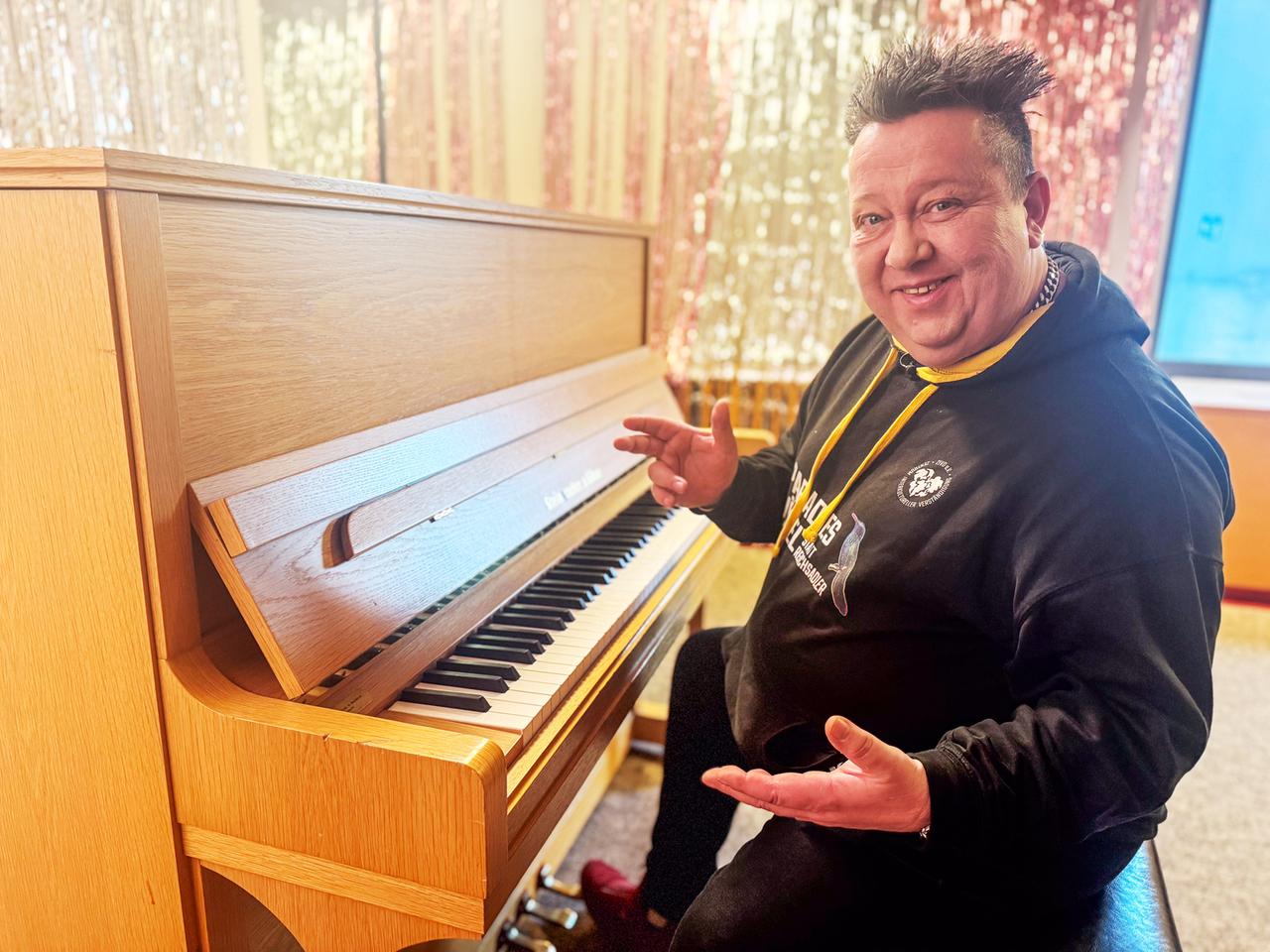 Sebastian Krumbiegel sitzt am Klavier und lächelt in die Kamera.