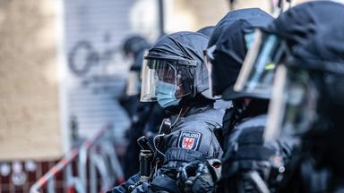 Drei Polizisten mit Helmen und gepanzerten Schutzuniformen