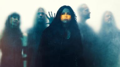Amy Lee steht vor einer milchigen Wand. Dahinter steht der Rest der Band Evanescence.