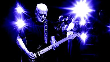 David Gilmour steht auf einer Bühne und spielt Gitarre.