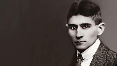 Historisches schwarz-weiß-Foto von einem ernst dreinschauenden jungen Mann im Tweed-Anzug mit Hemd und Krawatte.