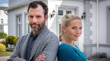 Ein Mann und eine Frau lehnen mit verschränkten Armen und Rücken und Rücken aneinander.