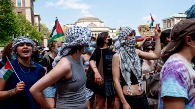 Junge Menschen protestieren mit palästinensischen Tüchern und Flaggen.