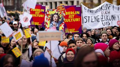 Menschen halten Plakate und Schilder bei Demonstration