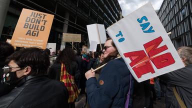 Demonstranten halten Schilder gegen KI hoch.