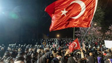 Polizisten mit Plexiglasschilden drängen von links gegen Demonstranten mit Schildern und türkischen Flaggen.