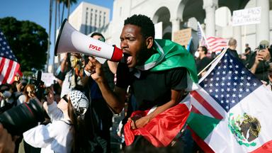 Mann ruft in Megaphon, eingehüllt in eine Flagge