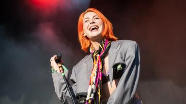 Eine Frau an einem Mikrofonständer lacht.