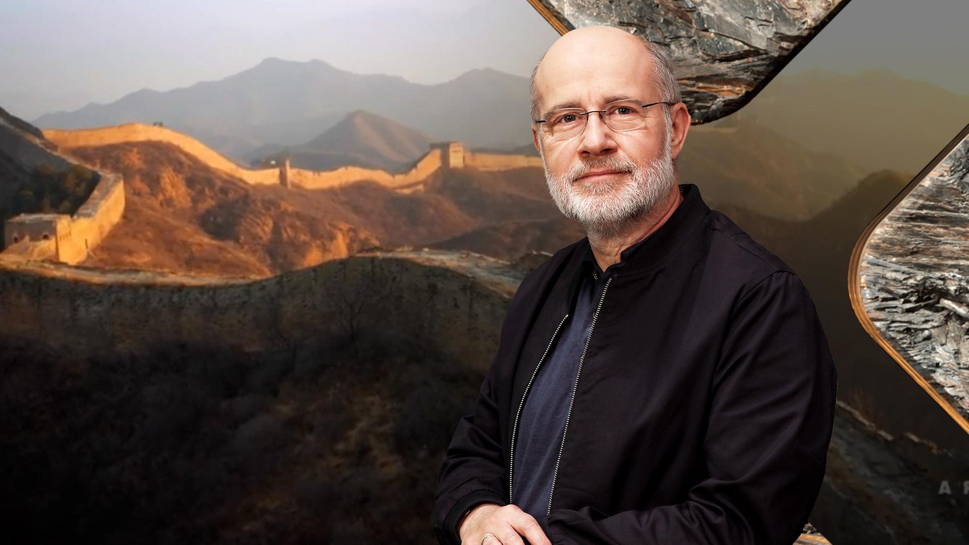 Harald Lesch schaut in die Kamera, links im Hintergrund ist die chinesische Mauer zu sehen.