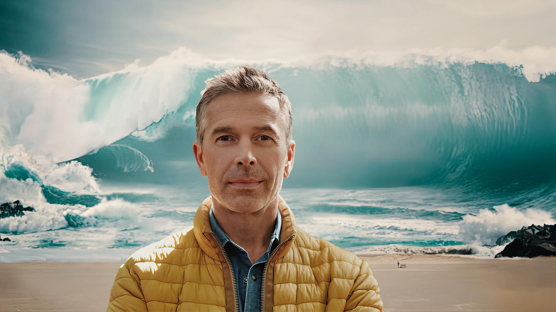 Dirk Steffens im Vordergrund, riesige Welle im Hintergrund