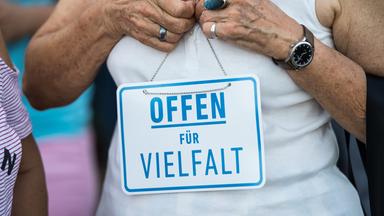 Eine Frau hält ein Schild in den Händen mit der Aufschrift:" Offen für Vielfalt".