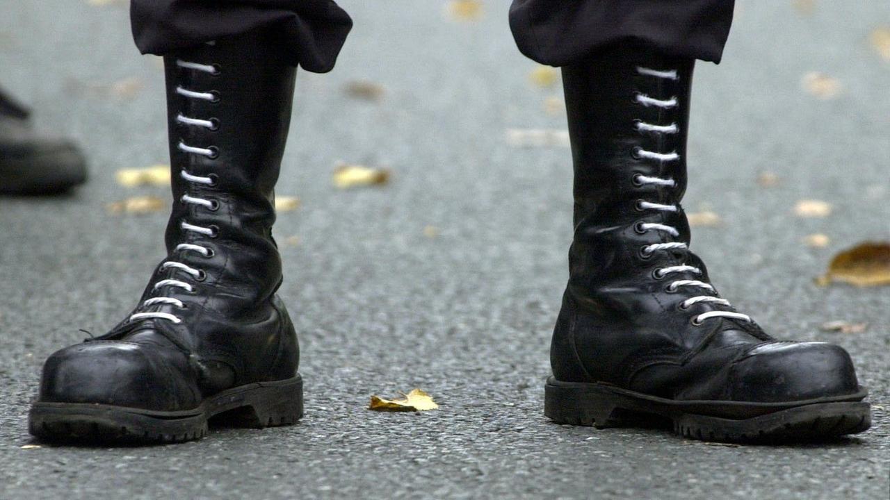 Zwei Füße in Springerstiefeln stehen auf dem Asphalt. 
