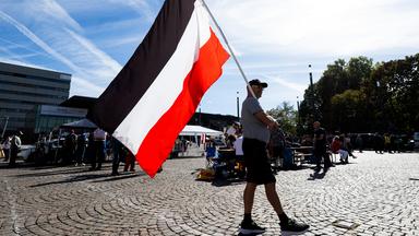 Mann läuft mit Flagge des deutschen Kaiserreichs über einen Platz