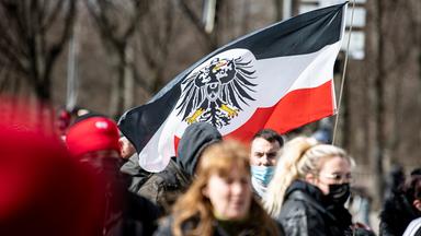 Berlin: Teilnehmer einer Demonstration von Rechtsextremisten und sogenannten Reichsbürgern laufen mit einer Flagge aus dem Kaiserreich die Straße des 17. Juni entlang.
