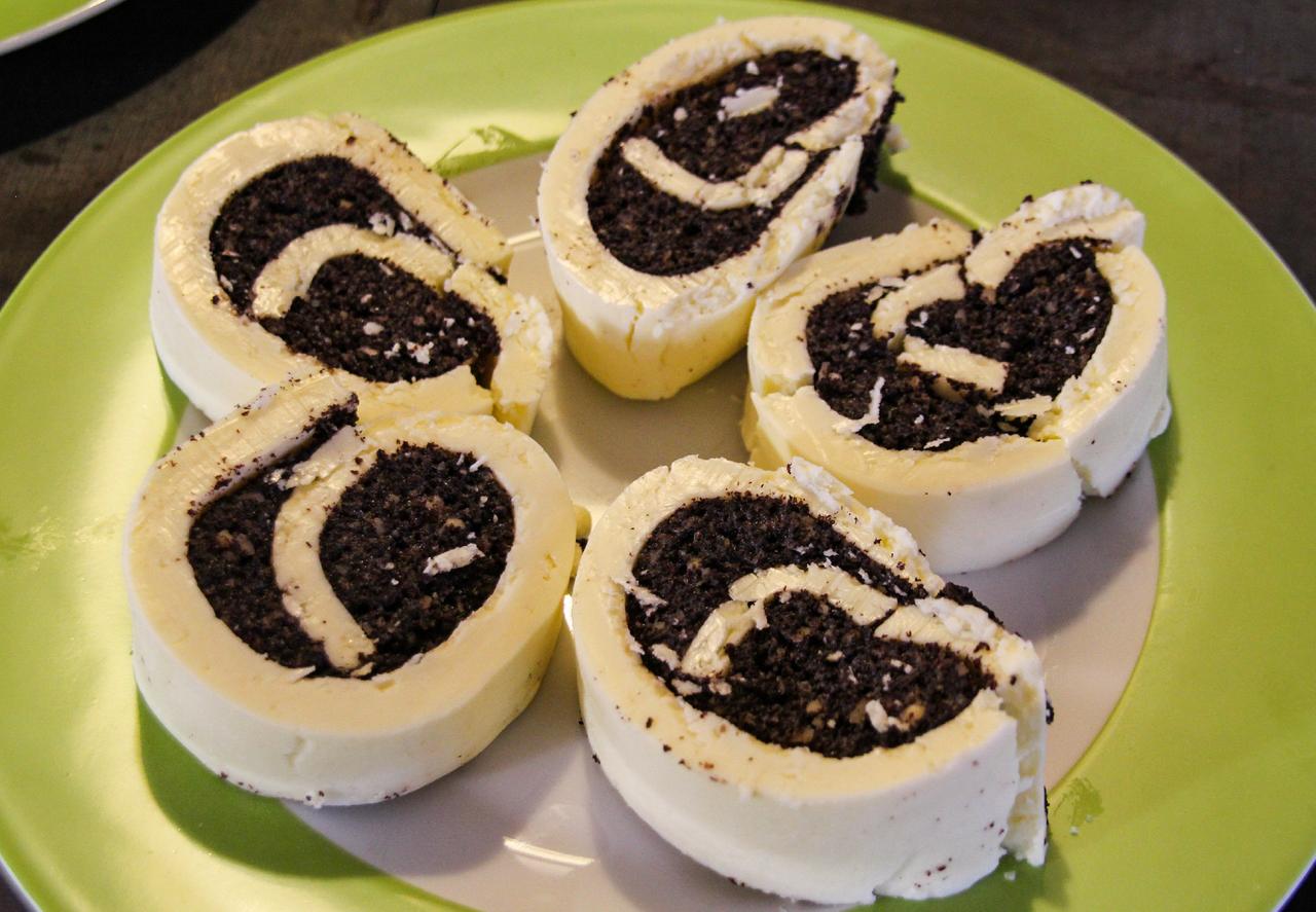 Mit Mohn gefüllte Rolle aus Butter auf Teller angerichtet