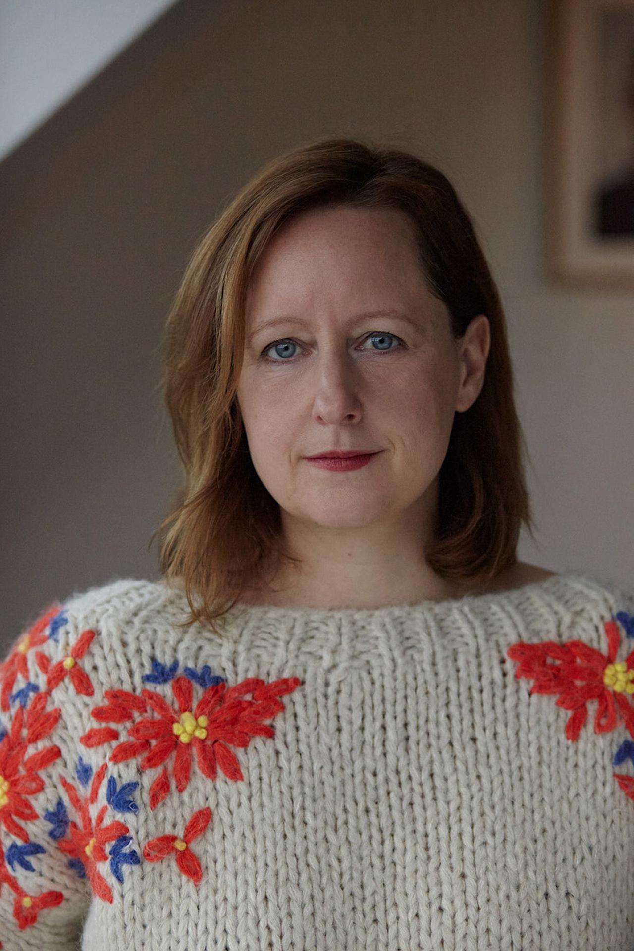 Frau mit halblangen Haaren lächelt in die Kamera.