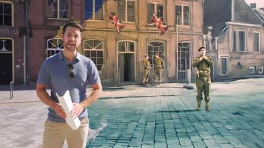 Moderator Mirko Drotschmann steht mit Dokumenten in der Hand vor einem historischen Gebäude. Der Hintergrund zeigt eine Montage mit britischen Soldaten und Union-Jack-Fahnen aus einer Graphic Novel.