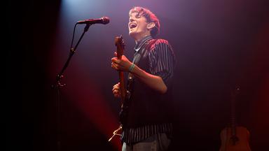 Ein Mann spielt Gitarre und singt in ein Mikrofon.