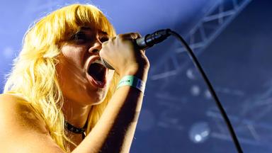 Eine blonde Frau singt in ein Handmikrofon.