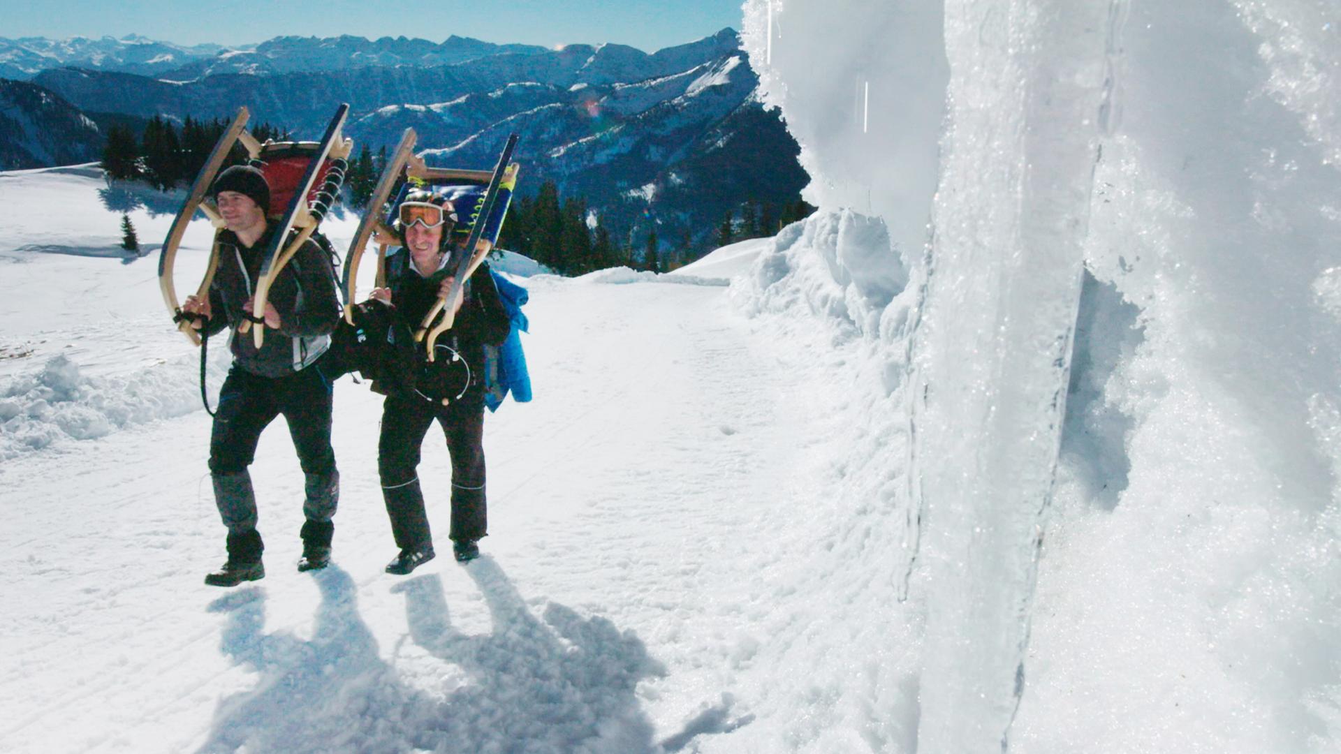Raimund Höfer (rechts) und Stefan Niedermeier tragen ihre Schlitten bergauf durch die verschneite Landschaft