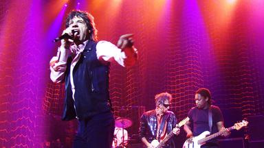 Mick Jagger singt auf der Bühne. Im Hintergund ist der Rest der Rolling Stones zu sehen.