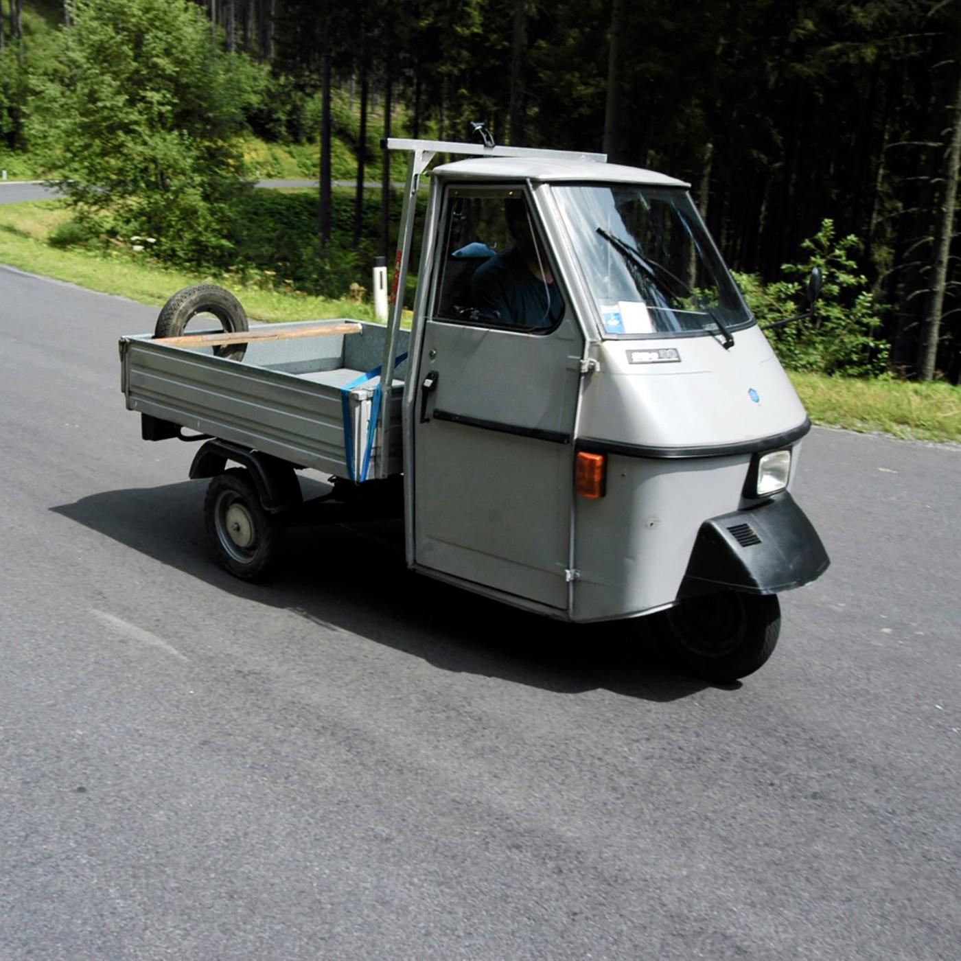 Ein kleines, dreirädriges Auto fährt eine Staße entlang