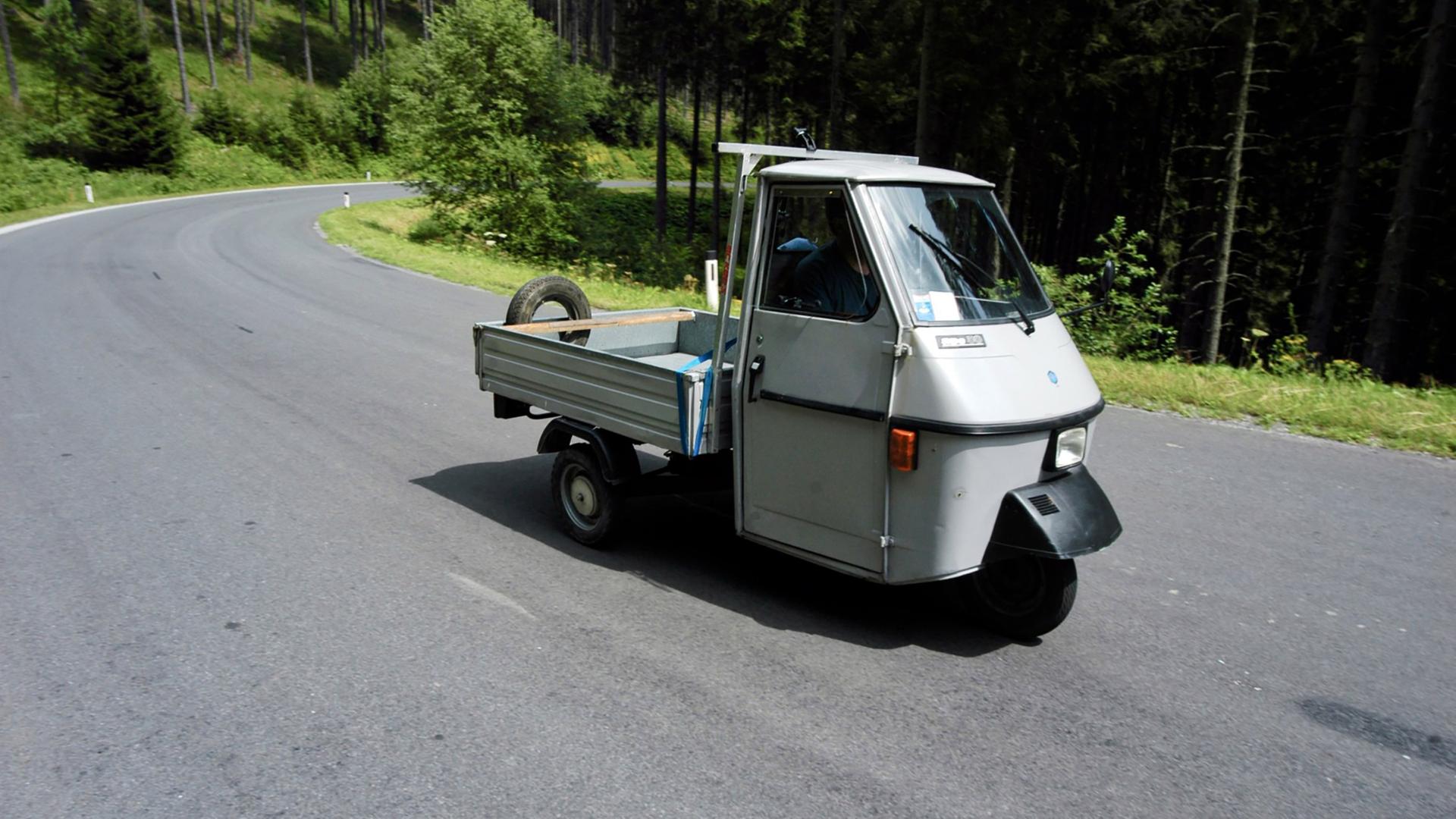 Ein kleines, dreirädriges Auto fährt eine Staße entlang