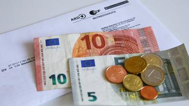 Geldscheine und Münzen auf einem Brief des Beitragsservice