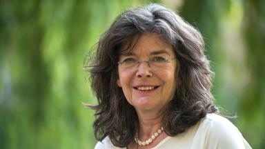 Eine Frau mit langen schwarz-grauen Haaren und Brille.