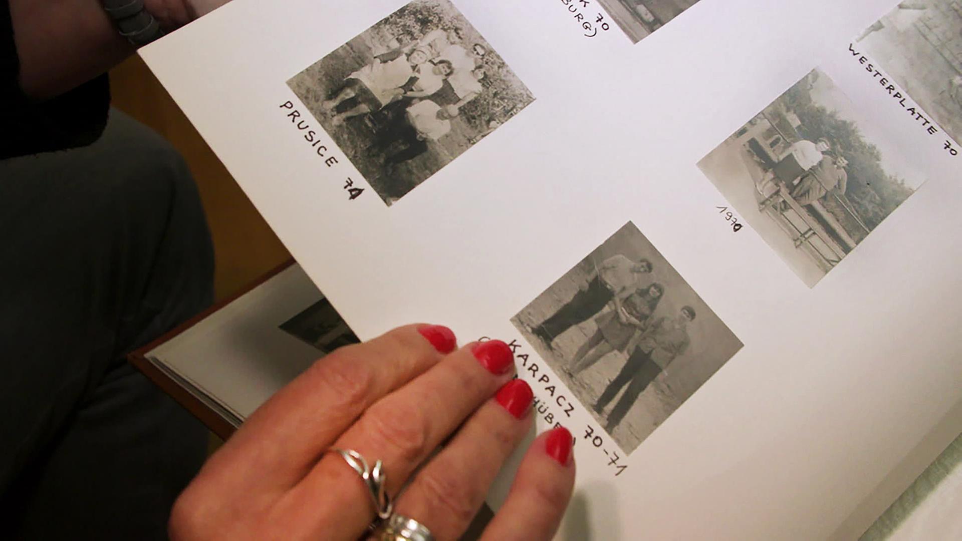 Ein Finger deutet auf Fotos in einem Familienalbum.