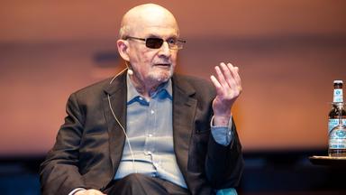 Ein älterer Mann mit graumeliertem Bart und einem geschwärzten Brillenglas.