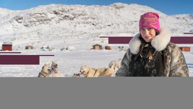 Salwa Houmsi in Sisimiut, der zweitgrößten Stadt Grönlands. Sie steht in einer Schneelandschaft, hinter ihr sind Schlittenhunde zu sehen.