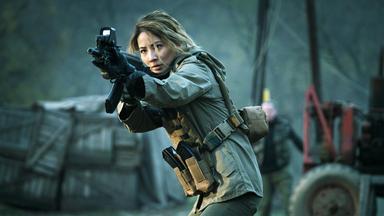 Zada (Jing Lusi) läuft angespannt mit einem Gewehr.