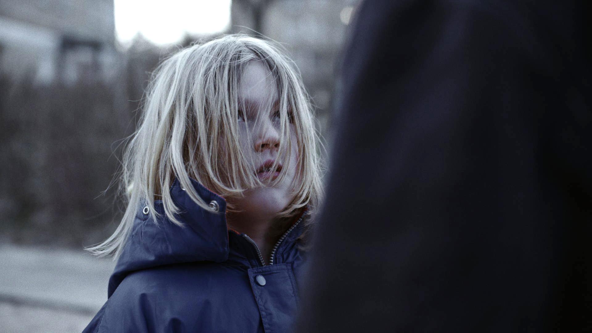 Ein blondes Kind mit Haaren, die ihm ins Gesicht fallen.