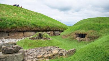Touristen auf einem Hügelgrab in Irland. 