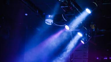 Scheinwerfer an der Decke eines dunklen Raumes die blaues Licht nach unten werfen.