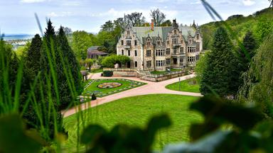 Blick auf ein Schloss inmitten eines akkurat angelegten Gartens.