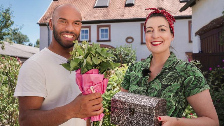junge Frau und junger Mann mit einer Pflanze und einer Truhe in der Hand.