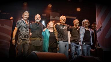 Menschen stehen Arm in Arm auf einer Bühne.