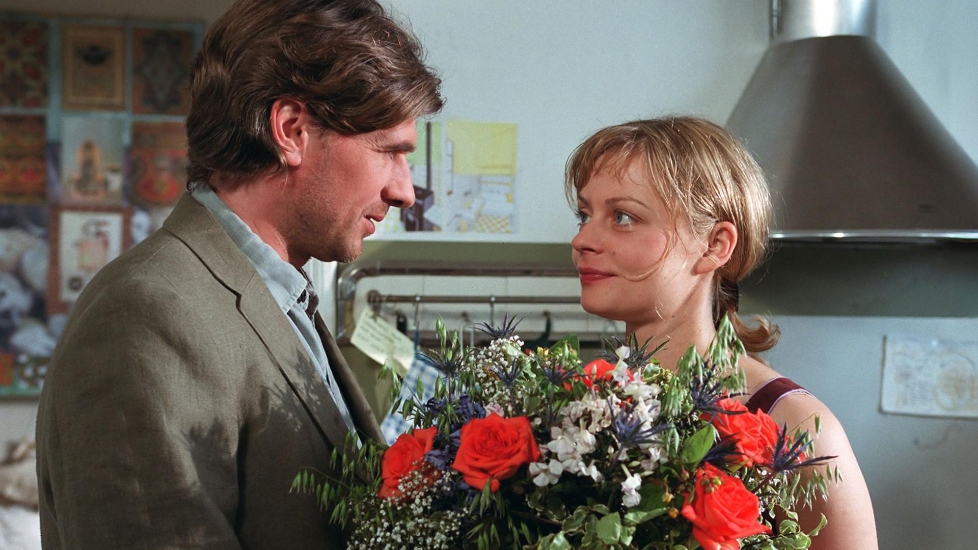 Ein Mann überreicht einer Frau einen riesigen Blumenstrauß.