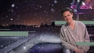 Jo Schück im Bademantel vor einem eisigen Wasserloch in Oulu / Finnland.