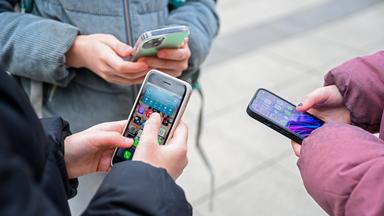 Drei Schülerinnen stehen mit Handys beisammen.