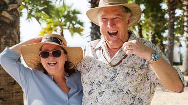 Ein älteres Paar lacht in die Kamera.