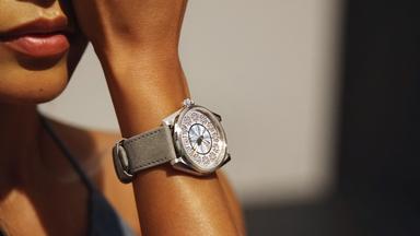 Eine Armbanduhr am gebräunten Arm einer Frau